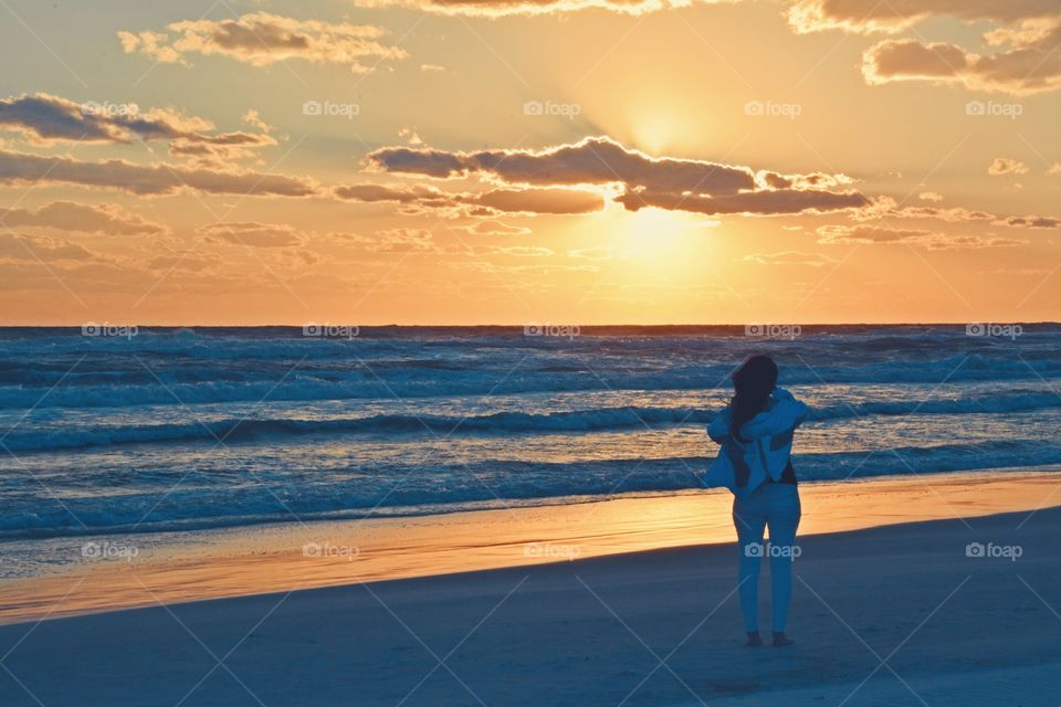 It was sunset. She watched with an unwavering gaze, as a fiery orange orb of light slowly sank beneath the horizon, and threads of light lingered in the sky, mingling with the clouds