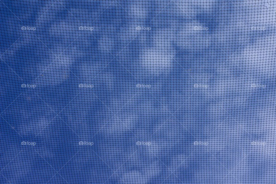 Looking skyward through  a thin mesh and viewing a beautiful blue sky and clouds in San Miguel de Allende, Mexico.