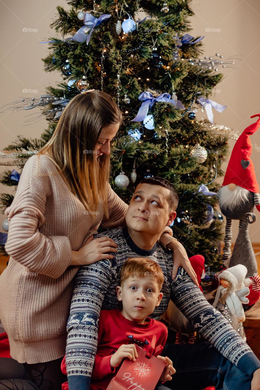 Cheerful family parents and son at home near the New Year tree