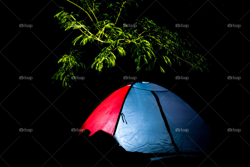 Picture of a tent with a flashlight inside with someone sleeping.