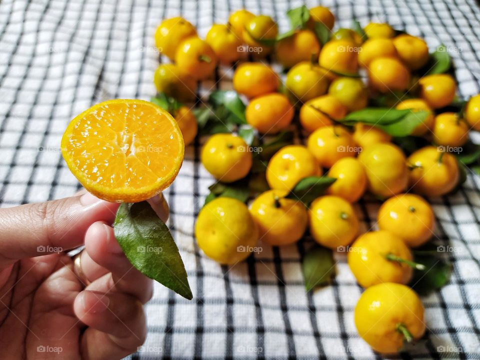 Fresh orange fruits with leaves as background, top view