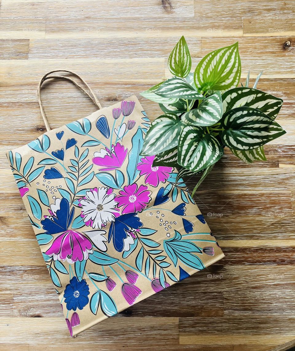 The delightfully decorated bag is 100% recycled, next to a green plant to remind us of what we’re doing this for - our planet.