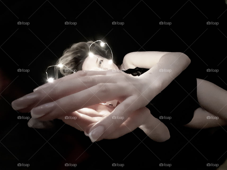 девушка лежит на черном фоне с гирляндой