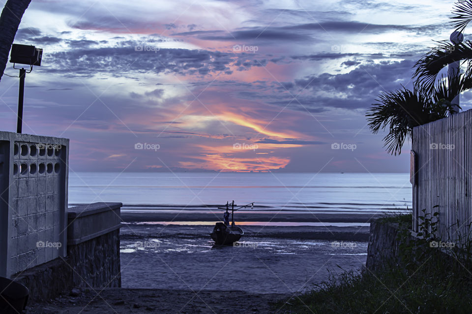 The morning sun light in the sea and the boat on the beach.