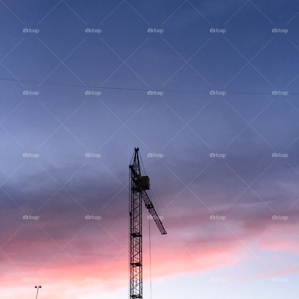 Construction crane against sunset sky