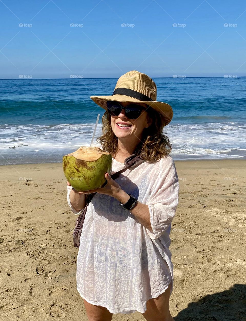 A beautiful woman enjoying chilled coconut water on the beach.