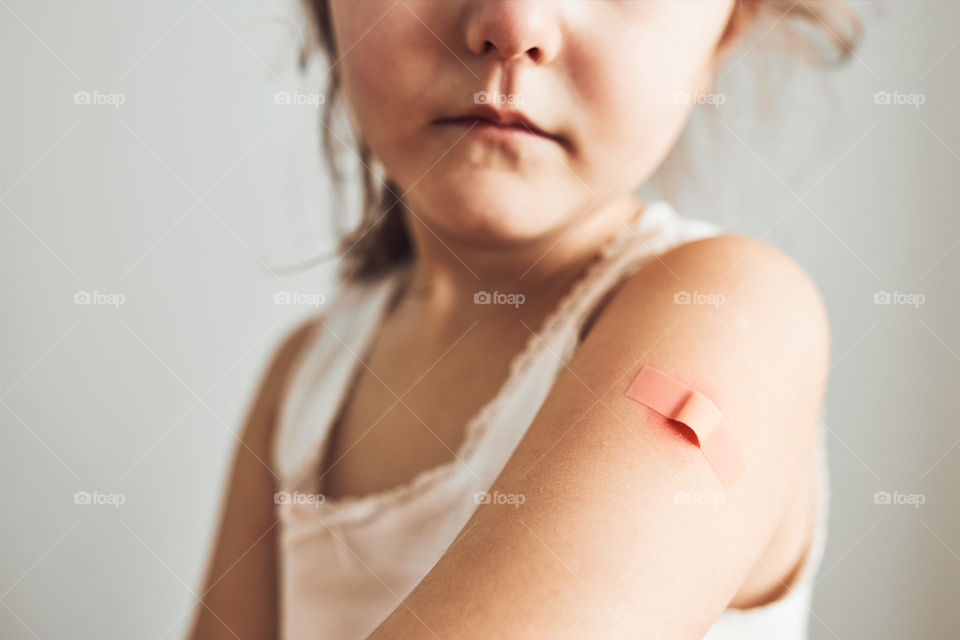 Little girl feeling pain having some side effects after vaccination. Redness, swelling, aching limbs and headache as reaction after vaccination. Getting a first injection. Healthy and medical concept