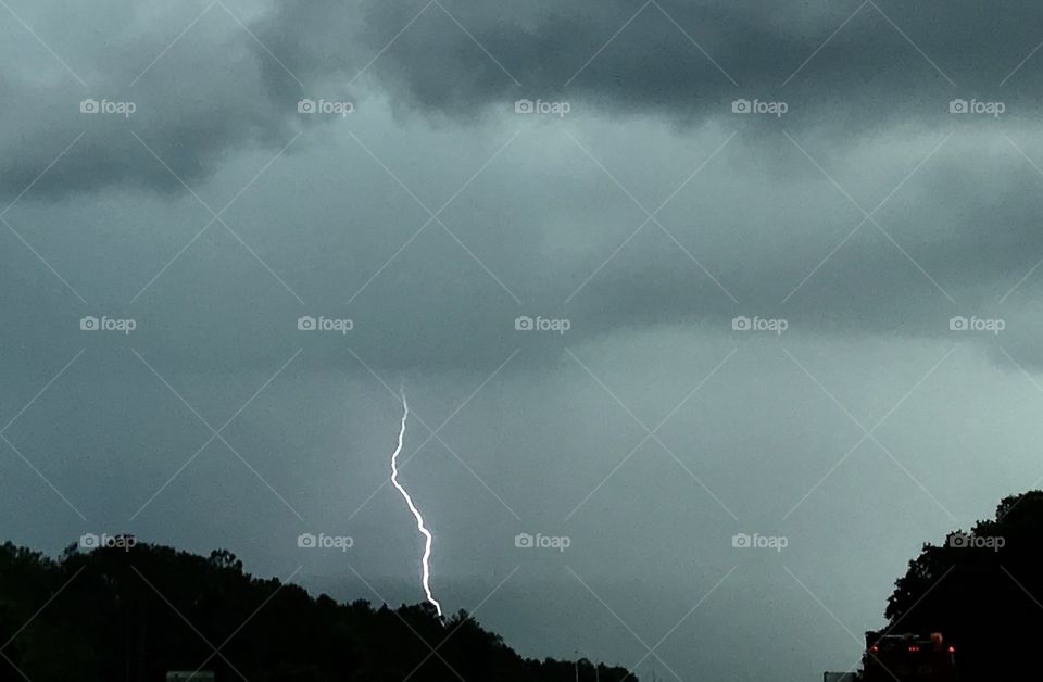 A dramatic single crack of lightening in the grey stormy sky 