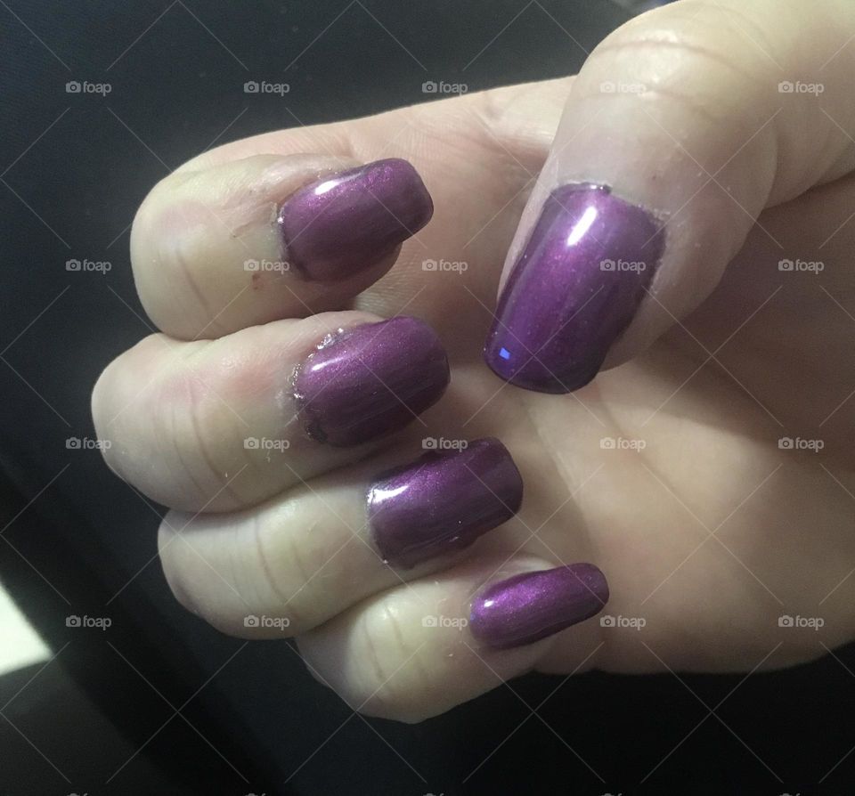 Middle aged ladies hand, pretending to hold something, showing her newly painted shiny purple gel nails