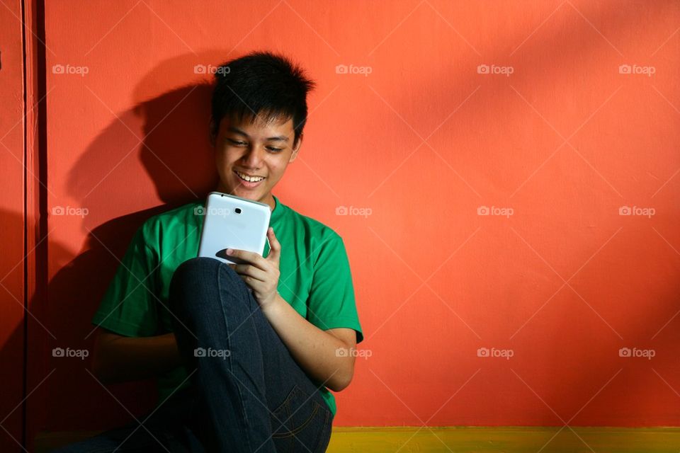 young asian teen with a tablet in a living room