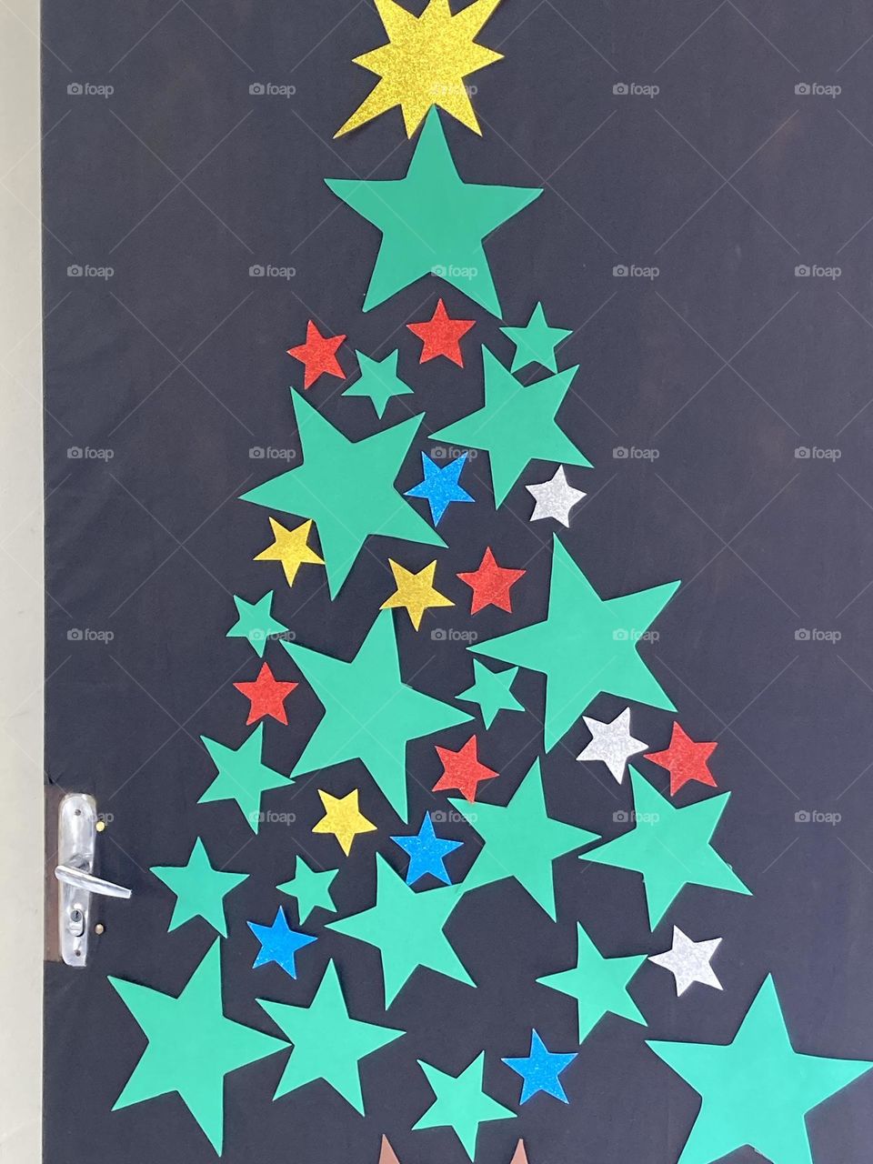 Porta enfeitada com motivos natalinos. Árvore de Natal na porta.