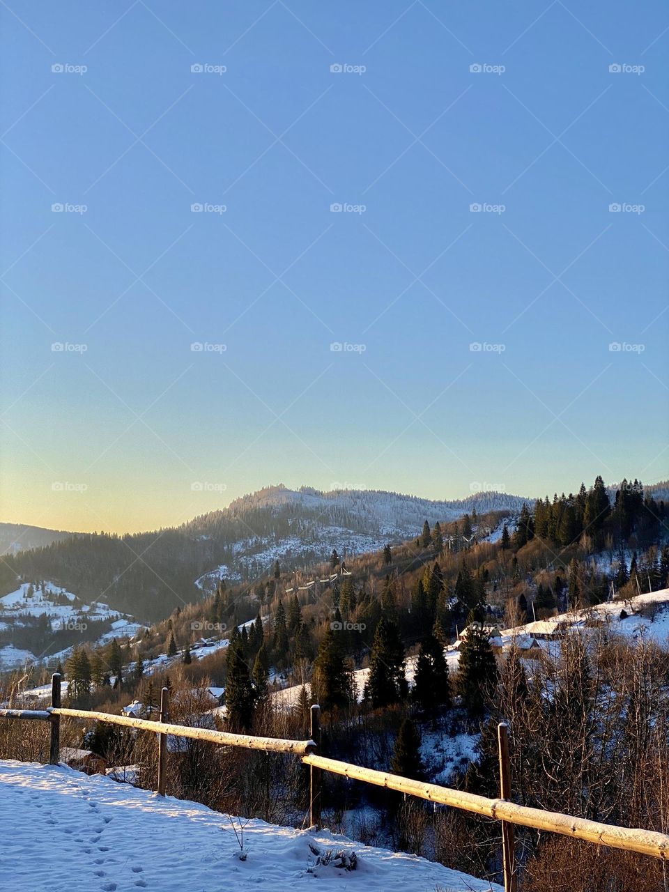 Photo of a sunny morning in the Carpathians in Ukraine. View from my window of winter mountains and snow-covered trees. Watching this live takes your breath away. The photo was taken on a phone.