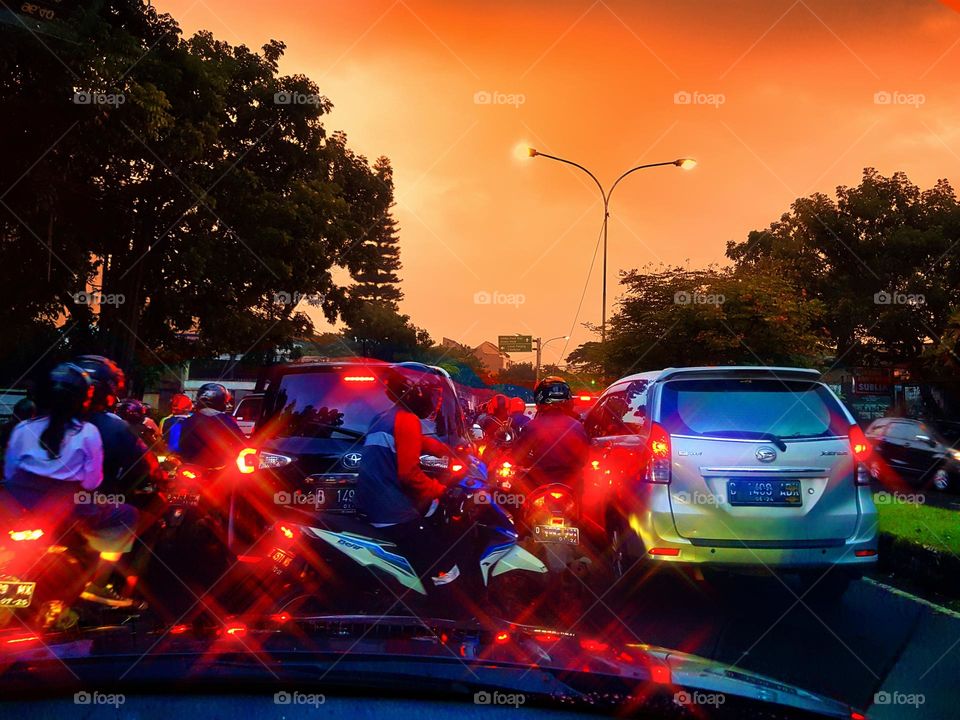 View of highway at night is cloudy, the road is quite busy, street are filled with motorbikes and cars, the vehicle light are very sprkling, emiting a bright red color, red dominates, the sky is cloudy, it refracts a reddish color, attractive outdoor