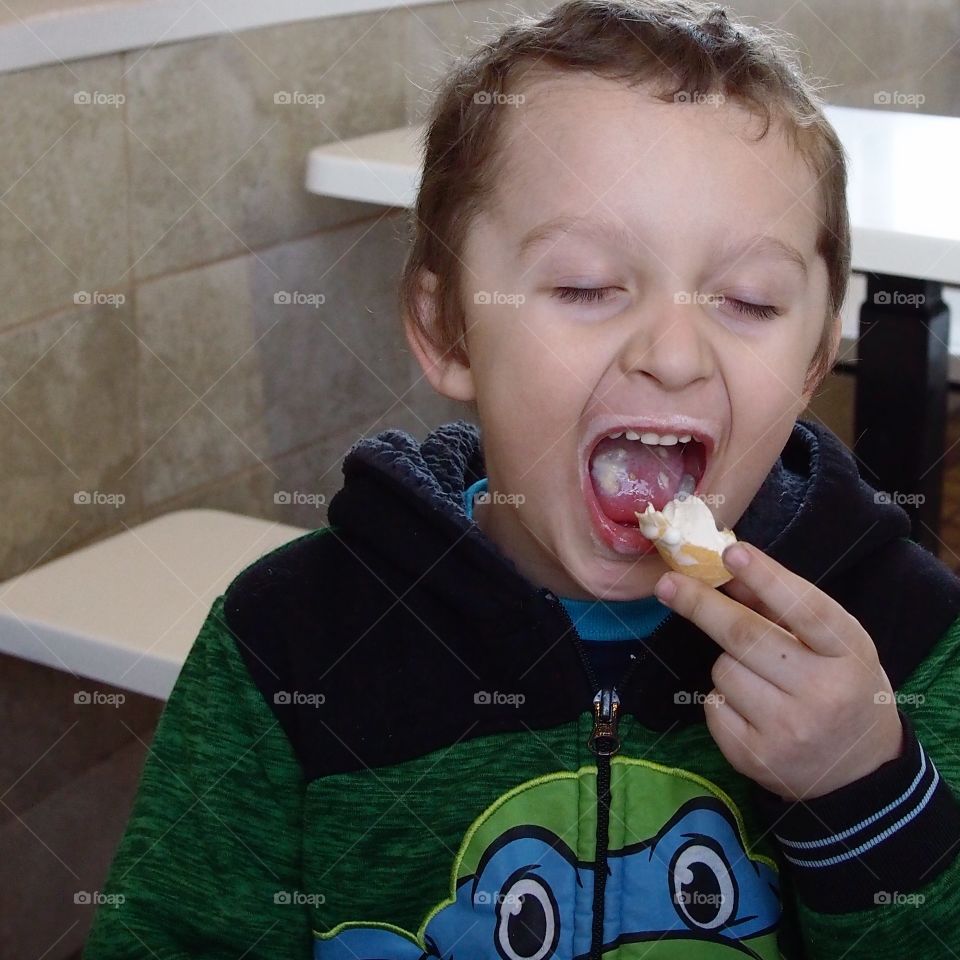 A little boy finishes one of his favorite treats....a vanilla ice cream cone. 