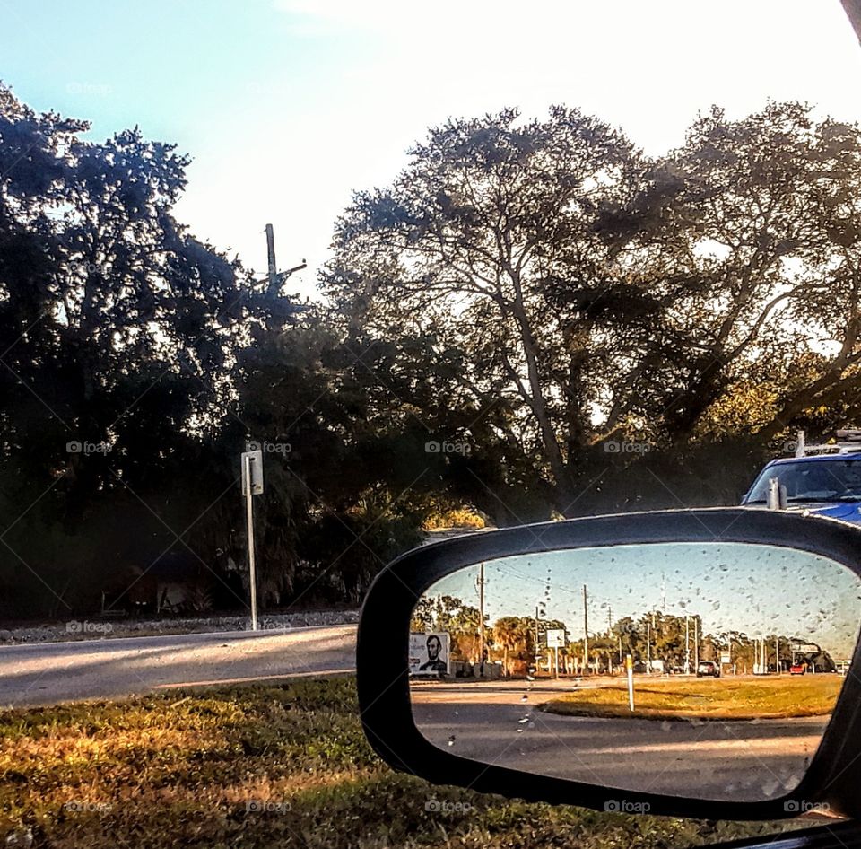 sideview mirror image off rural hwy at dawn.