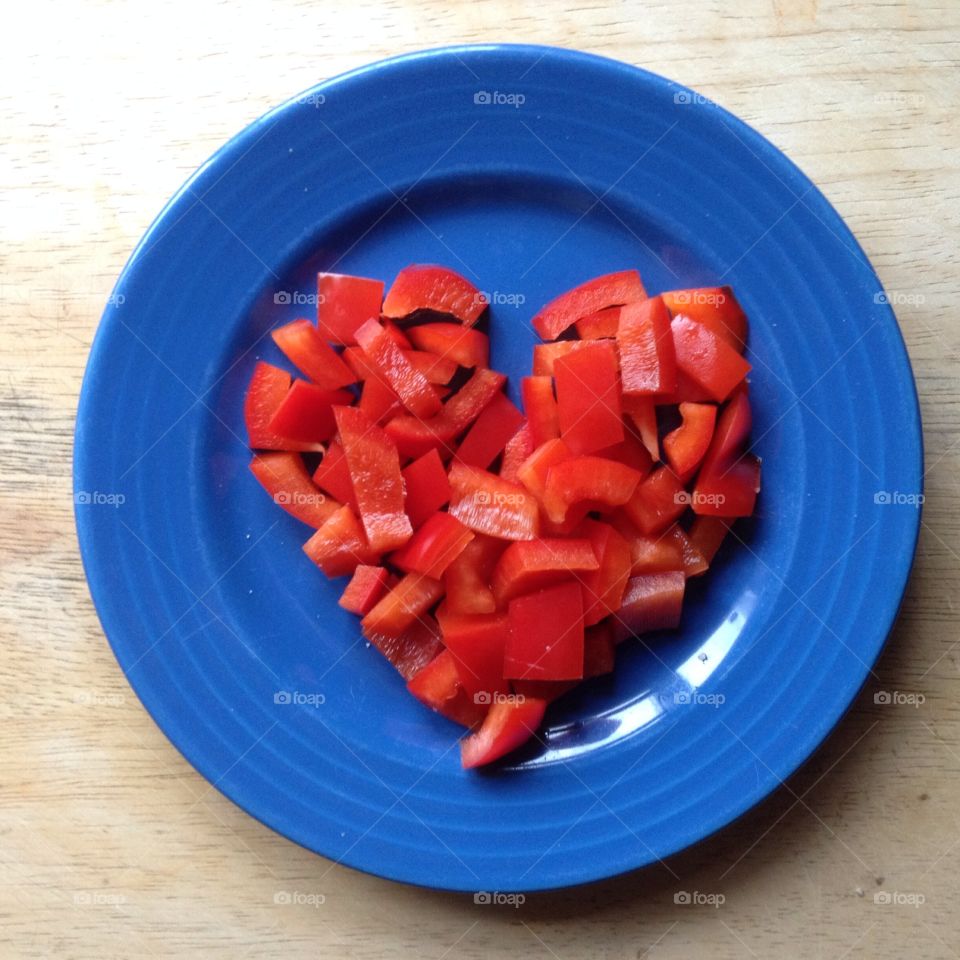 Heart shaped food. Heart shaped chopped red peppers on a blue plate
