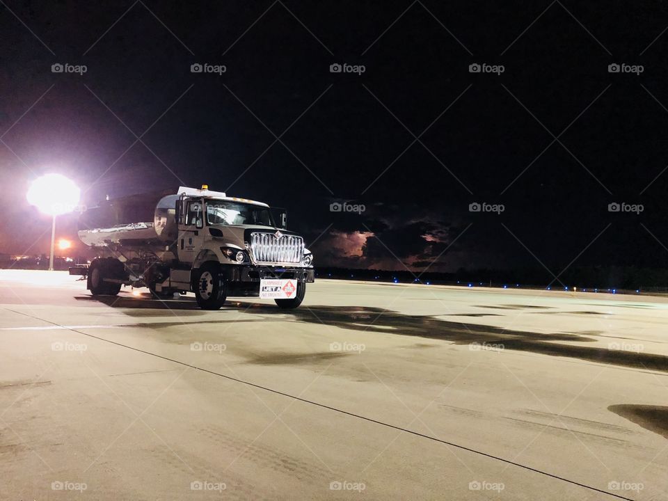 Fueling truck on the airport ramp with lightning in the background 