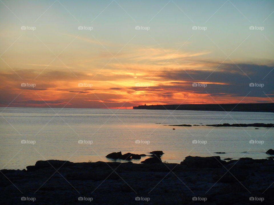 orange sunset on a sea stone shore summer time