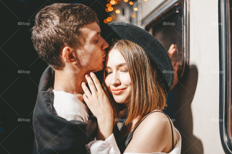 Young couple in love in stylish fashionable outfit romantic weekend wedding trip against background of camper in woods forest road trip