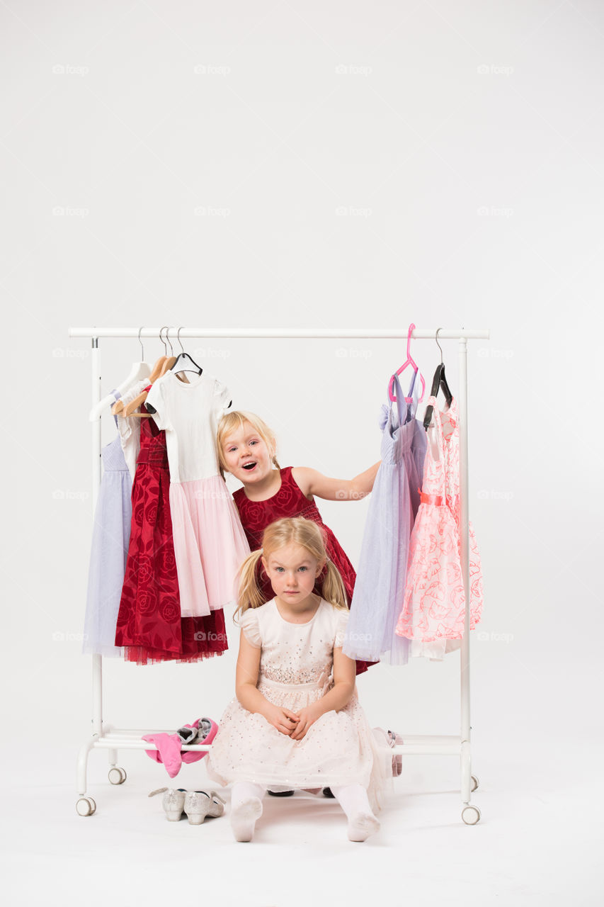 Two cute sisters is posing and playing with clothes and having fun.