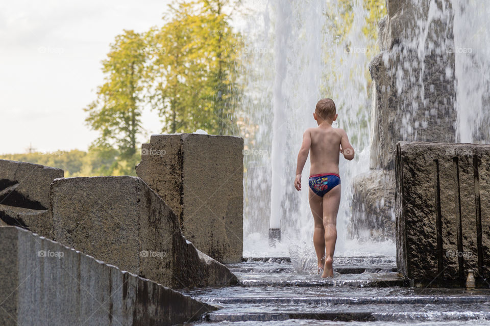 a boy playing in fountain