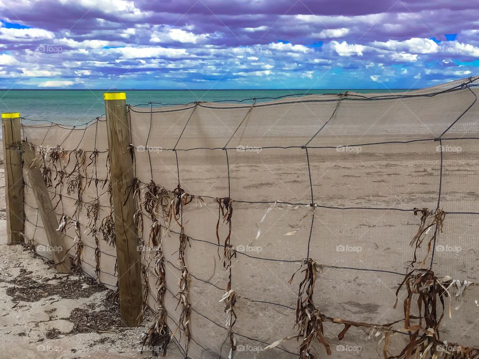 Long sand barrier fence on windy day on long stretch of beach in south Australia 