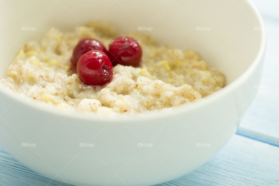 homemade oatmeal with frozen cherry on a blue wood background.  tasty and healthy  breakfast concept