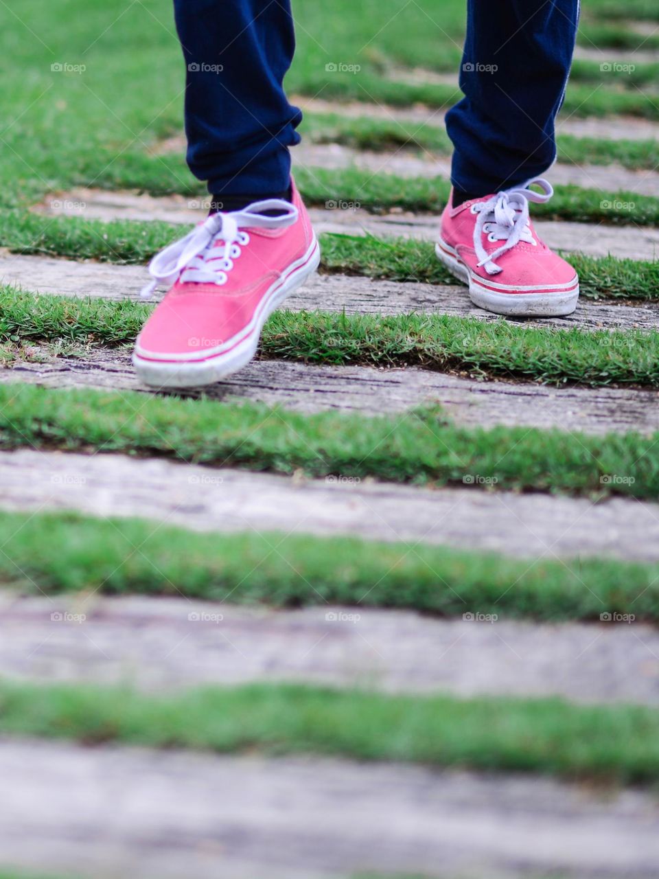 Pink sneakers taking one step at a time on wooden planks