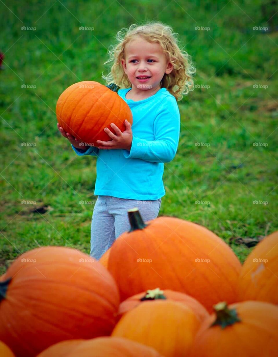 Heavy Pumpkin. Young girl carrying a heavy pumpkin. 