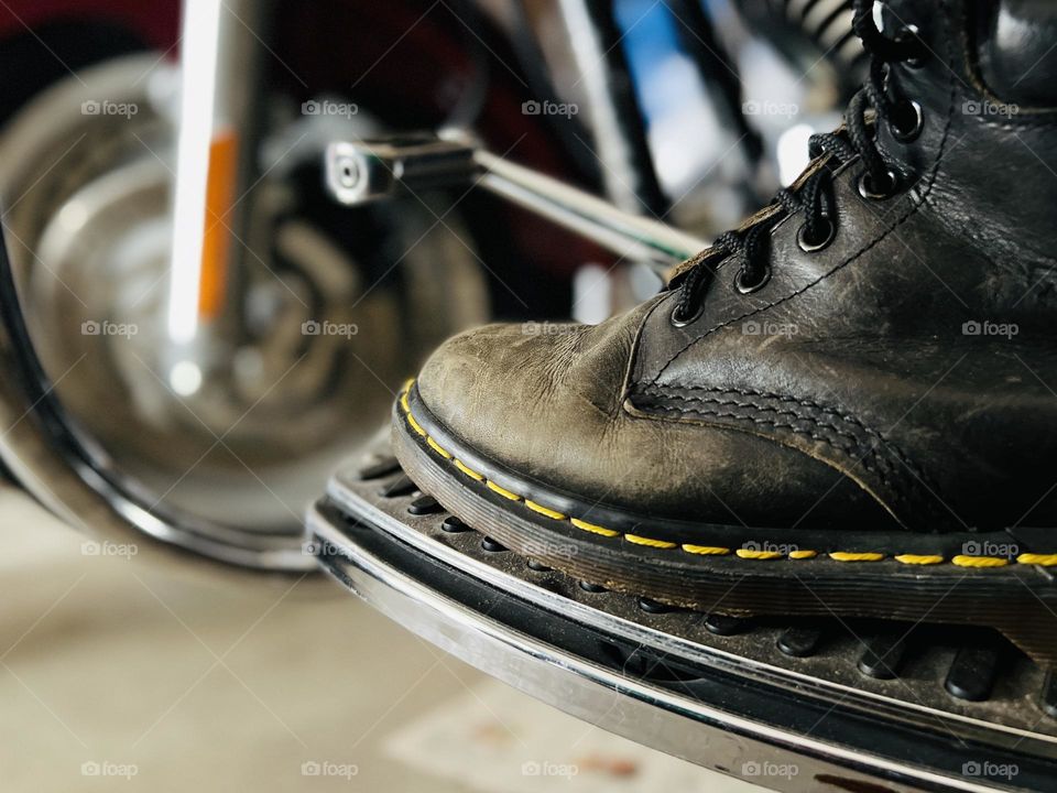 Closeup of worn, older Doc Marten classic boots with motorcycle in background 