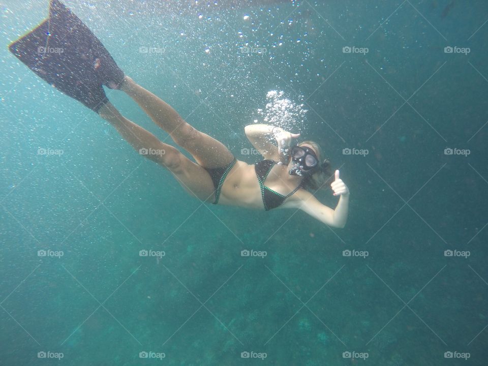 Snorkeling woman gesturing thumbs up underwater