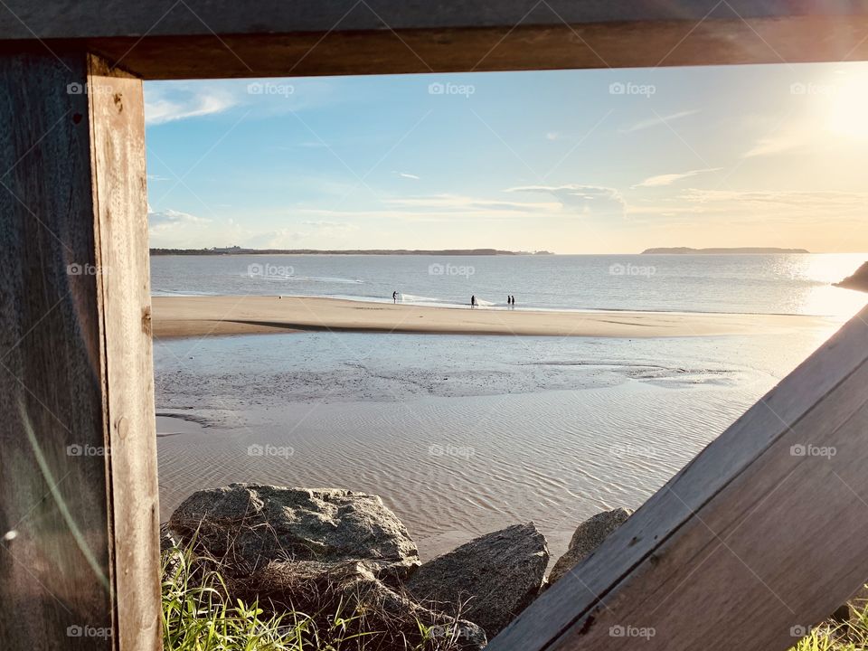 Wooden parapet, sun and  fishermen at the Beach 