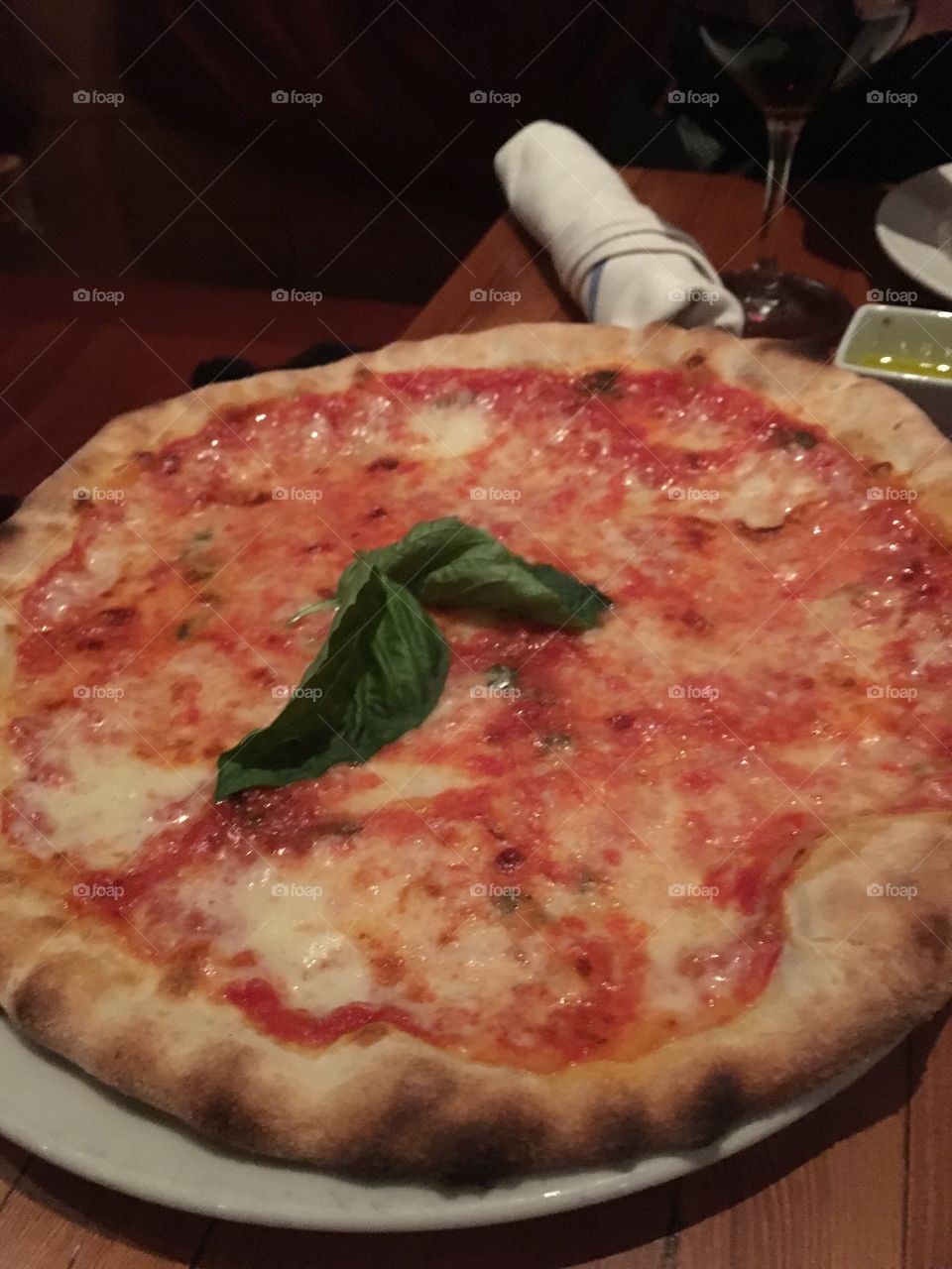 Brick oven tomato and cheese pizza topped with basil. Dinner at an Italian restaurant. 