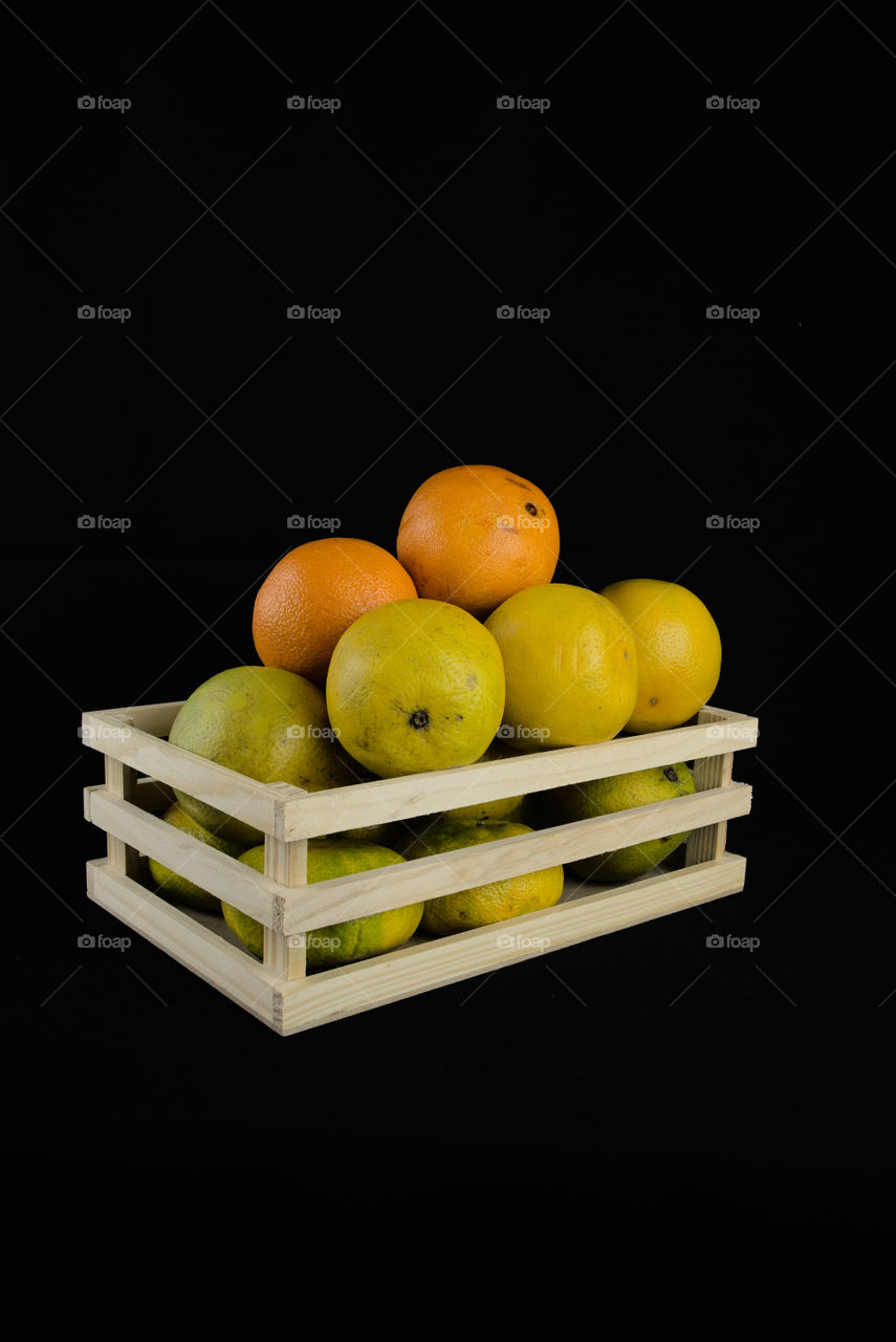 Wooden box with oranges on black background