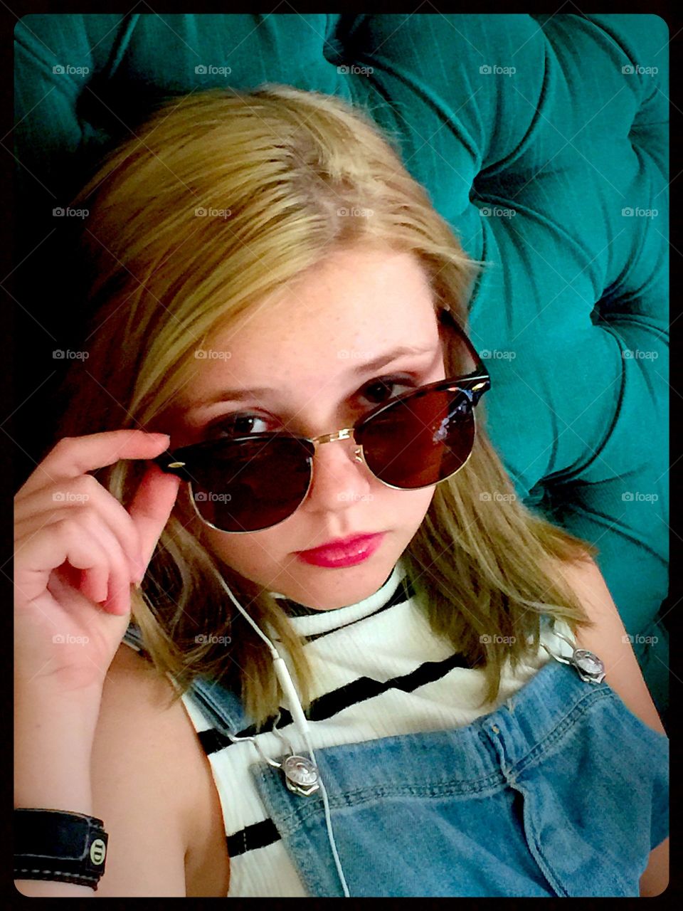 Girl in sunglasses with headphone sitting on sofa