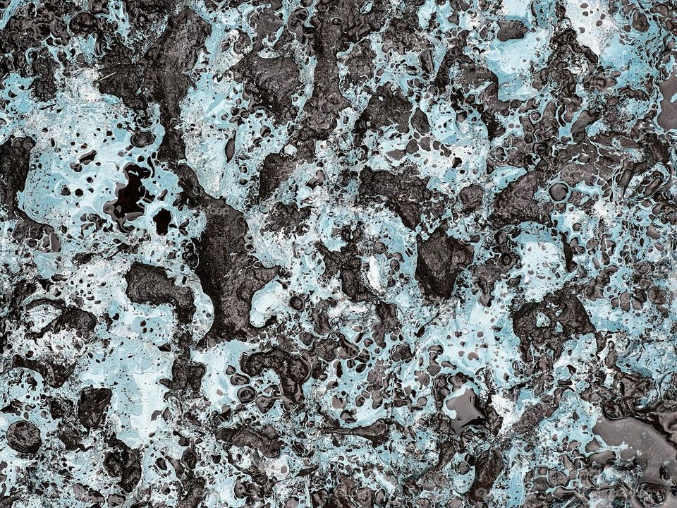 Close up of glacier ice over black lava stone