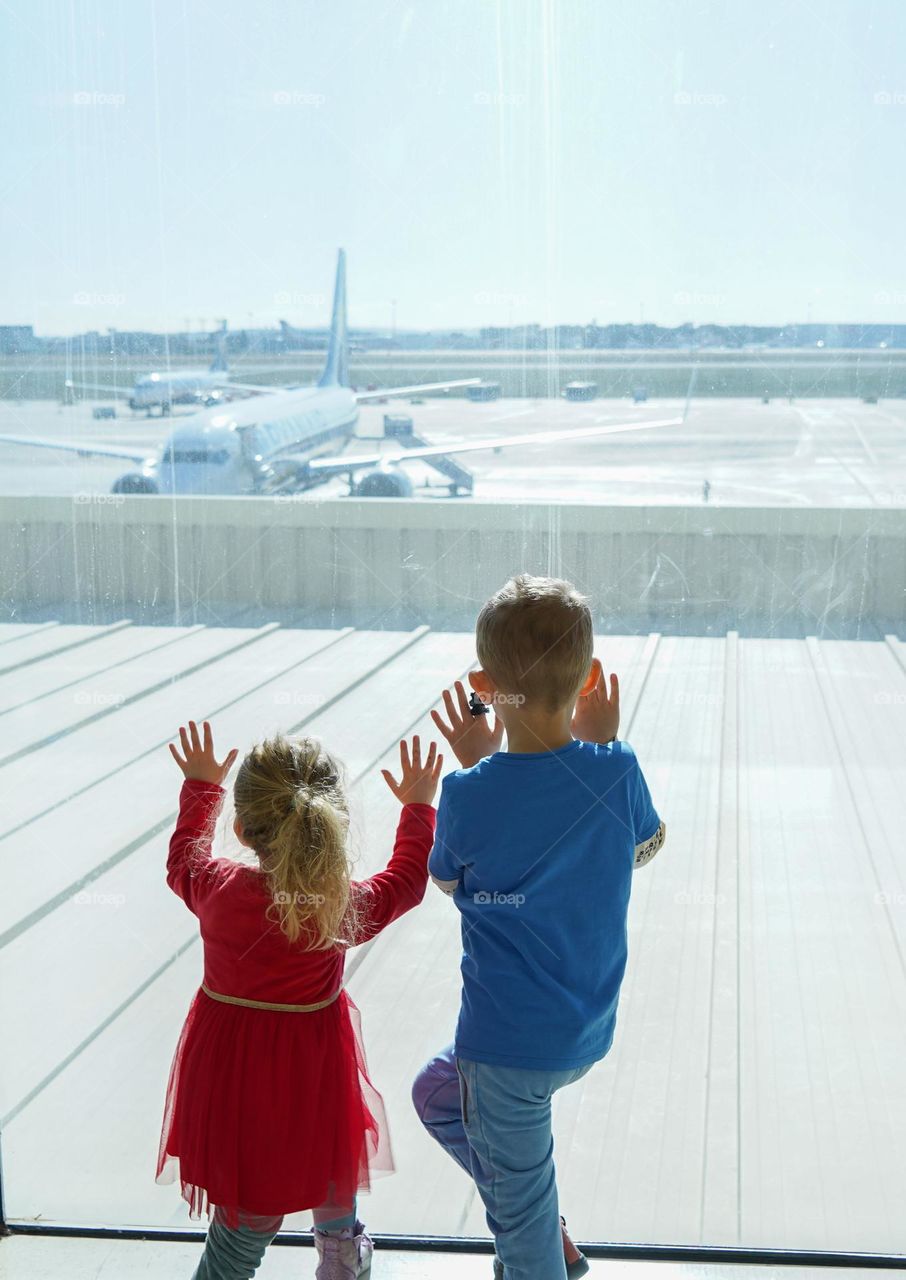 children looking through the window to the airplanes talking off