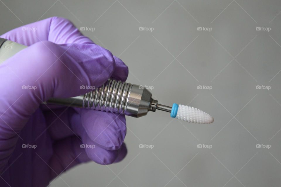 Manicure tools are held by a manicurist in rubber gloves