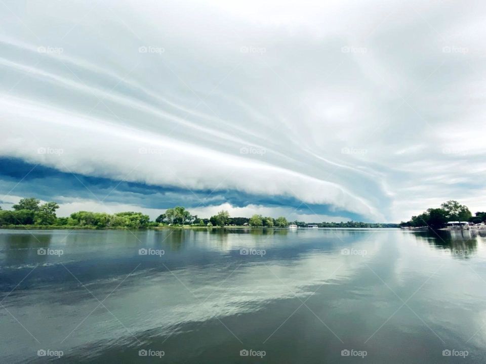 A shelf cloud rolls in over a lake creating an eerie cloud pattern
