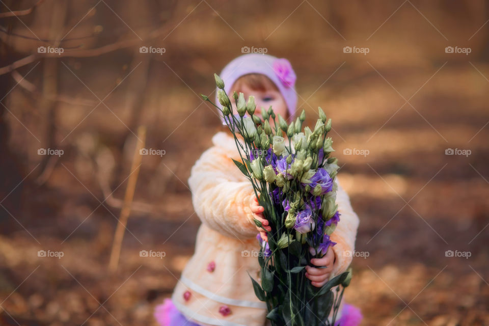 Little girl with bouquet of eustoma  flowers in spring park