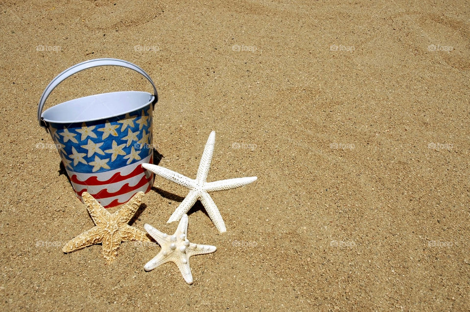 Starfish and beach bucket in the sand. 