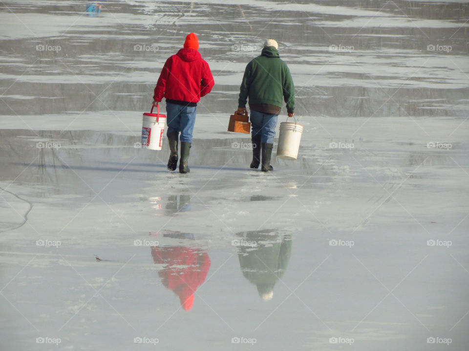 Two men captured from behind as they head out to ice fish on a frozen Ohio lake