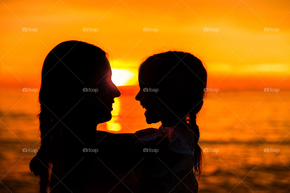 Silhouette of happy mother and daughter on sunset 