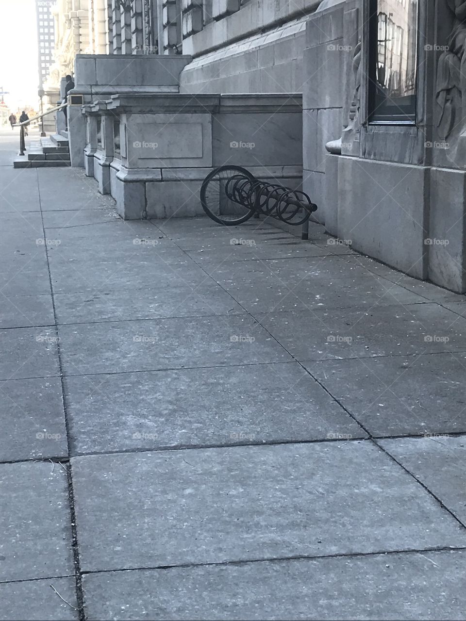 A lonely tire chained to a bike rack outside.