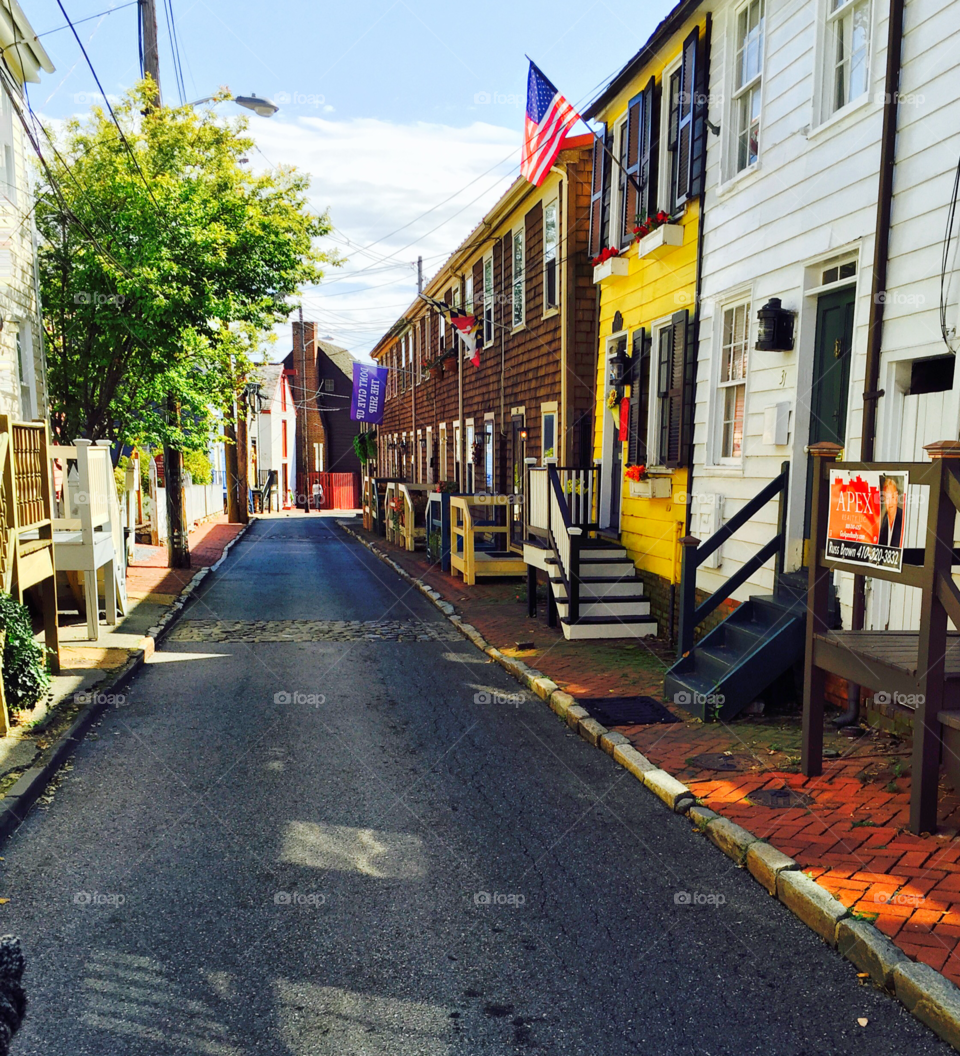 Annapolis city street. Cute row houses in a pretty little side street. Sunny day with blue sky. American flag flying. 