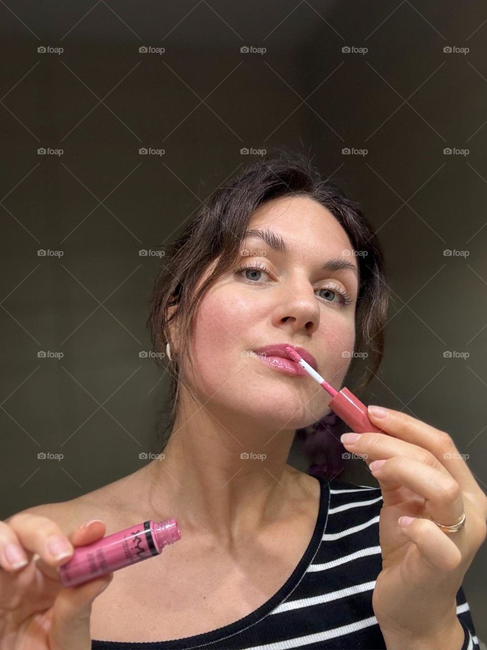 Woman’s portrait with product, girl holding a lipstick in her hands 
