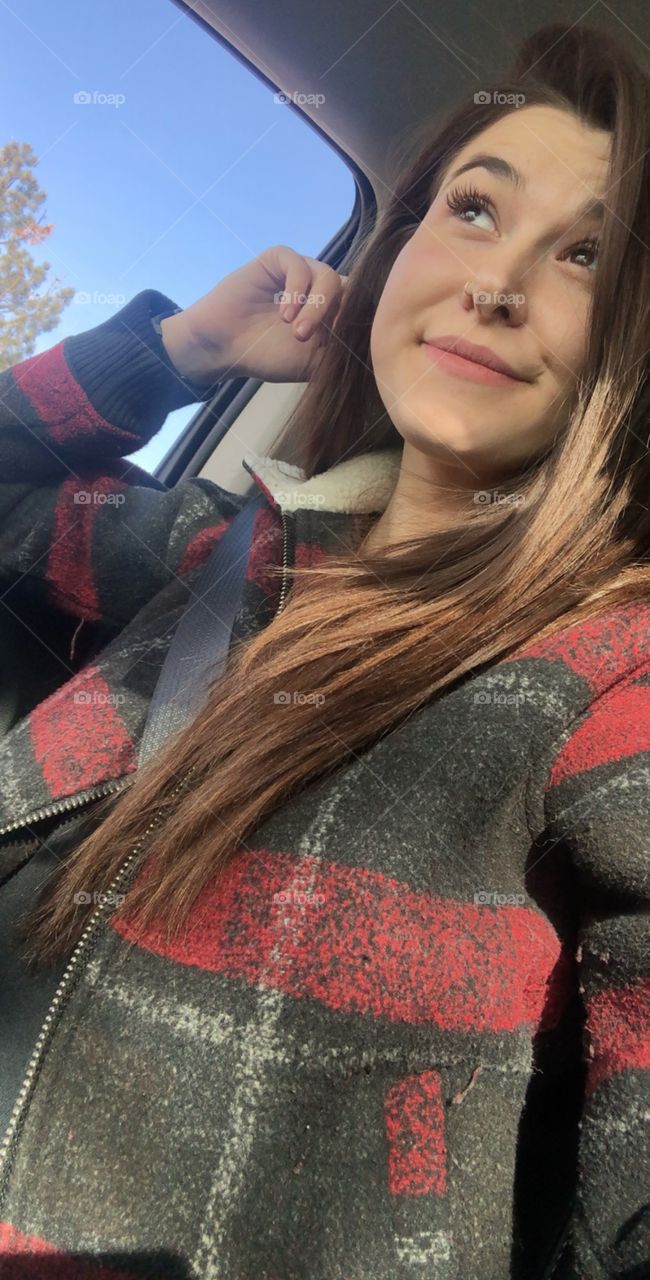 Brunette college girl sitting in her car listening to music. 