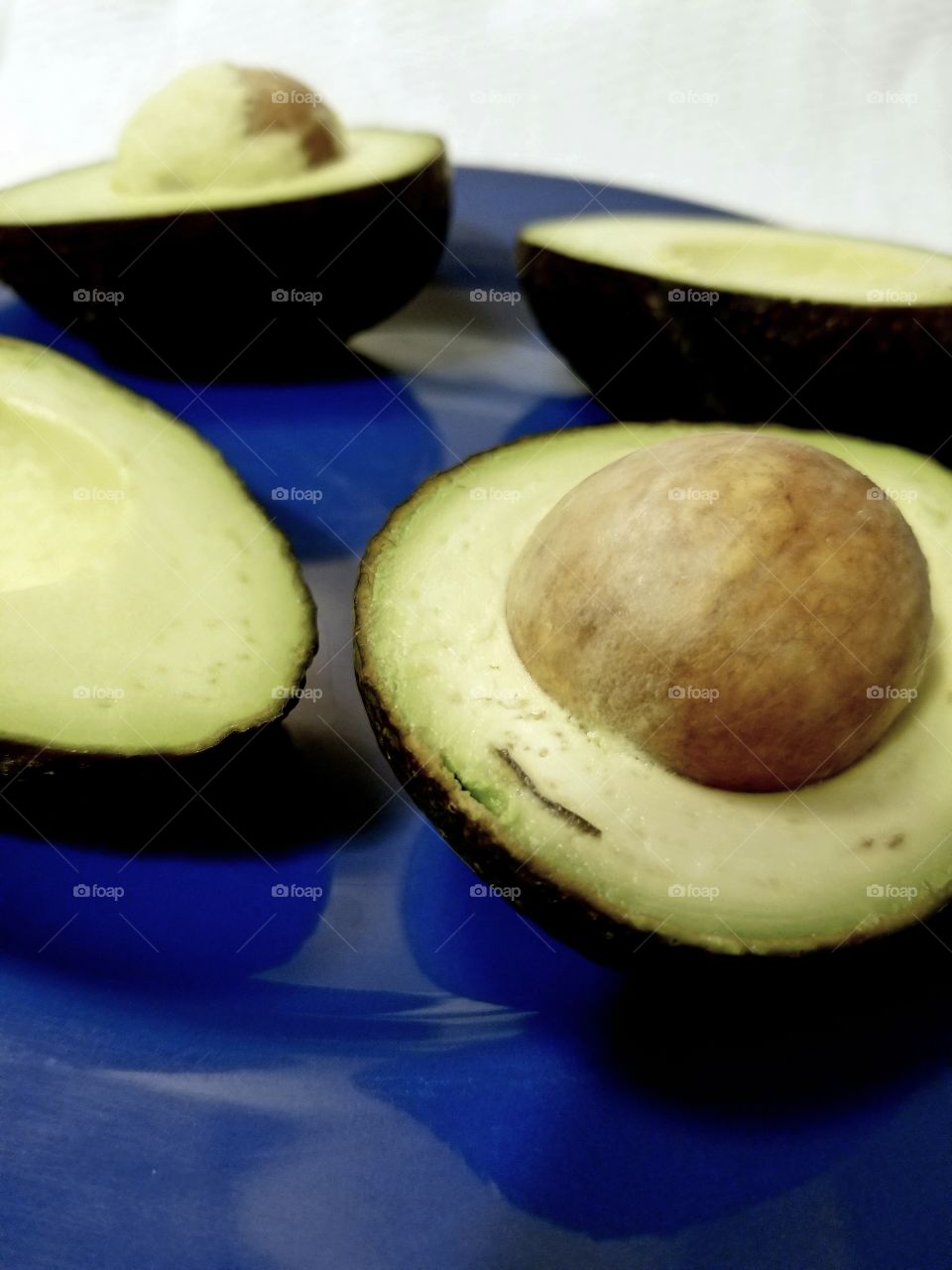 Halved, ripe avocados presented on a blue plate.