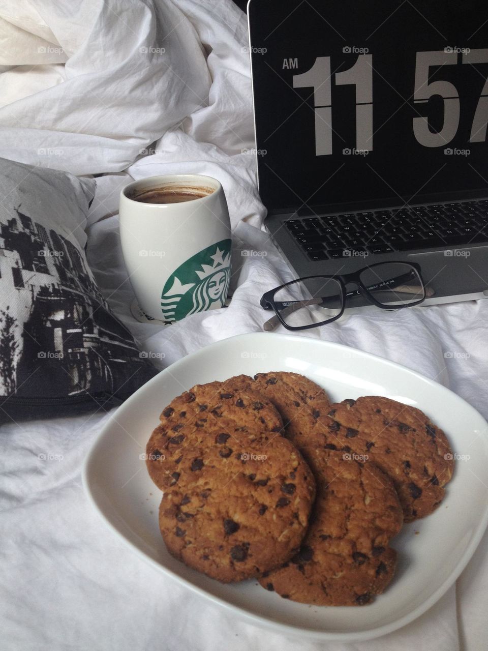 Eating food. Chocolate cookies, laptop, Starbucks cup of coffee on the bed. Breakfast in bed 