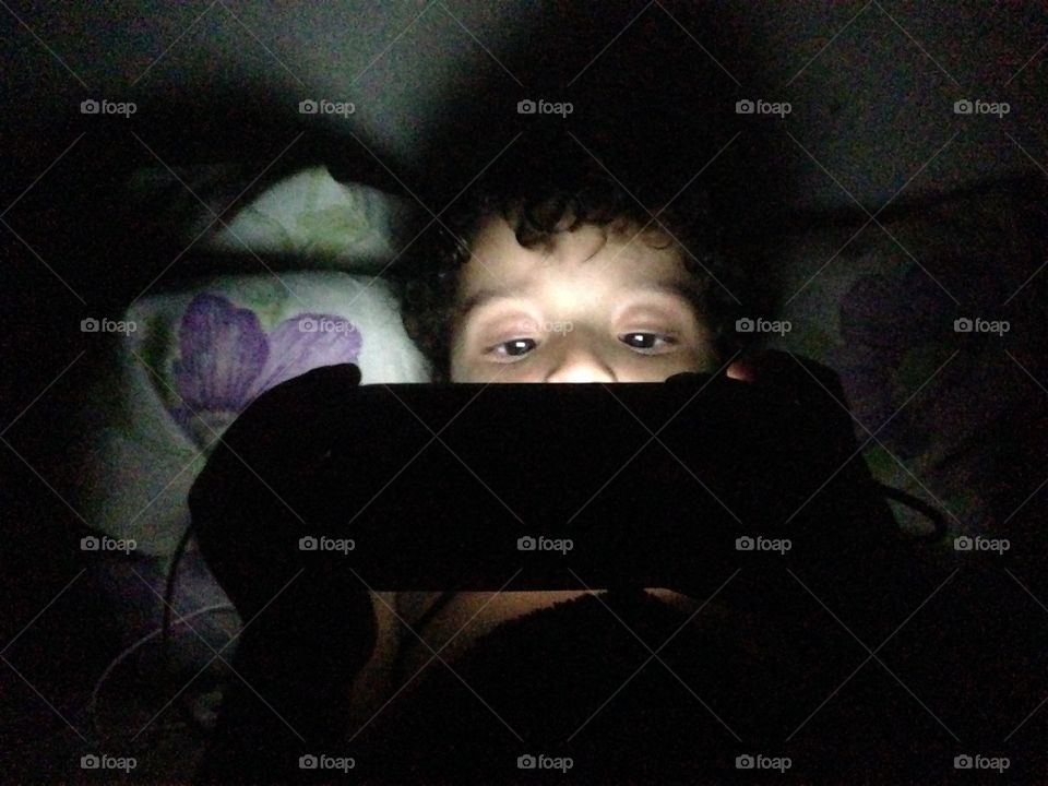 Boy lying on the bed and watching mobile